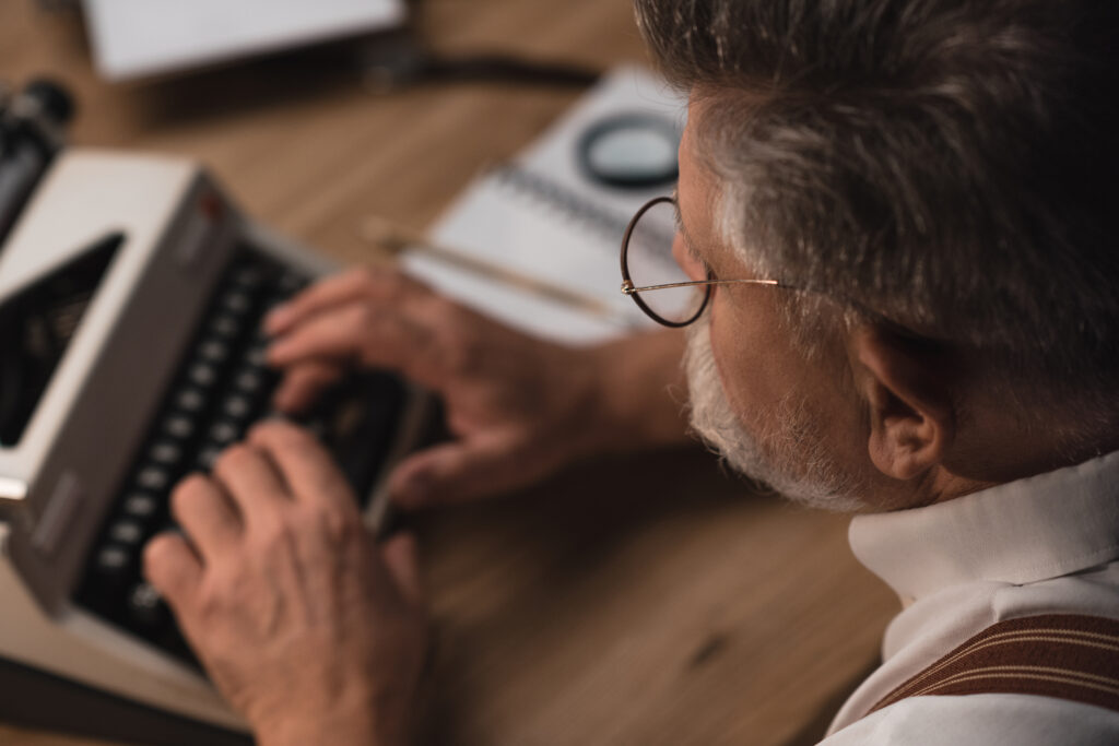 close-up shot of senior writer working with typewriter